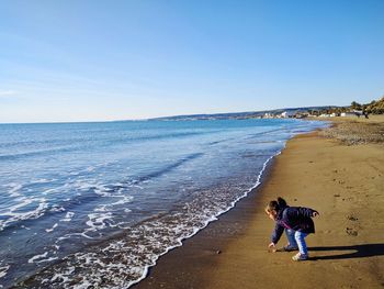 Girl playing at beach against clear sky