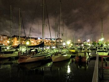 Boats moored at harbor against sky at night