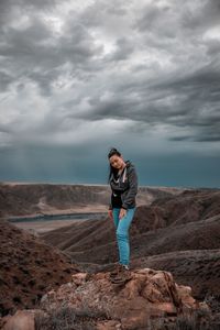 Full length of man standing on rock against sky