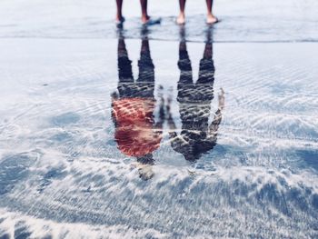 Low section of people standing on shore at beach