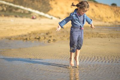 Full length of girl playing at beach