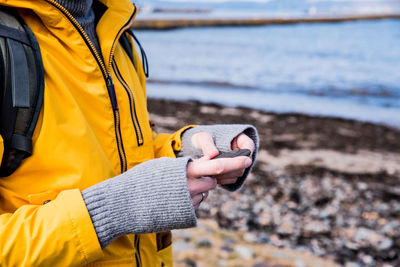 Midsection of man holding stone while standing at beach