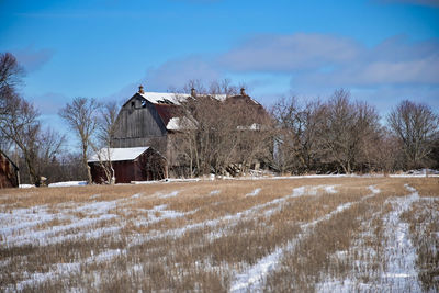 Snow covered field by houses against sky