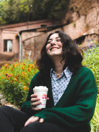 Young woman wearing sunglasses drinking outdoors