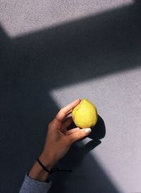 Cropped hand holding lemon on table