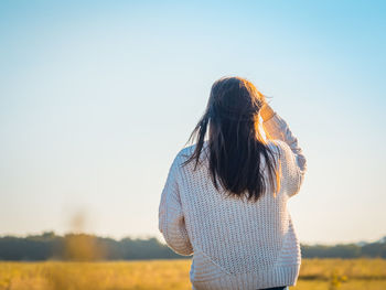 Rear view of woman standing against sky during sunset