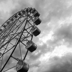 Low angle view of ferris wheel against cloudy sky