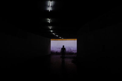 Silhouette man walking in illuminated tunnel