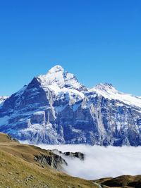 Scenic view of snowcapped mountains against clear blue sky