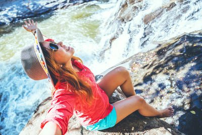 Midsection of young woman on rock at sea