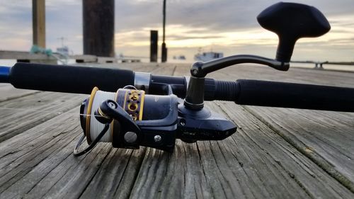 Close-up of motorcycle on boardwalk against sky