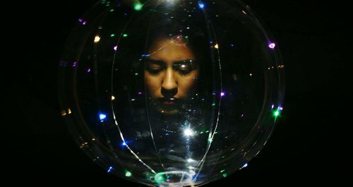 Woman seen through illuminated lighting equipment against black background