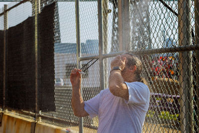 Water spraying on man standing by fence