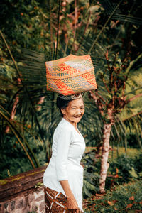 Woman wearing hat standing against trees