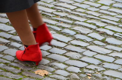 Low section of woman standing on cobblestone