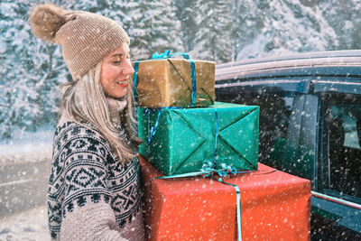 Woman giving gifts is holding presents delivering to home car holidays concept sunny cold winter day