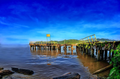 Pier over river against blue sky