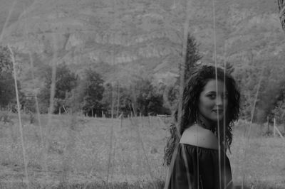 Portrait of woman standing on field against trees