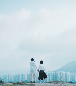 Rear view of women holding hands standing on hill