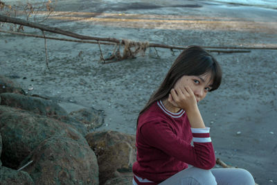 Portrait of girl sitting on rock by river