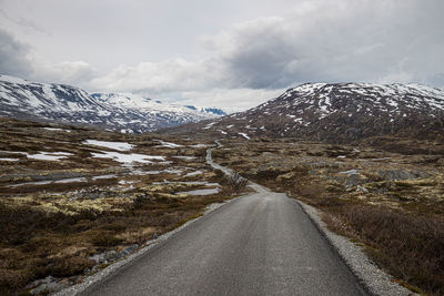 Road amidst snowcapped mountains against sky