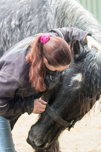 Woman standing by horse on field