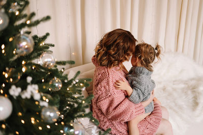 Rear view of woman standing against christmas tree