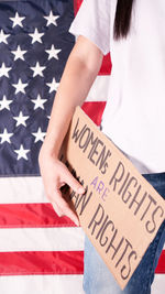 Woman holding sign women rights are human rights against american flag 