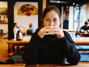 Portrait of woman having coffee while sitting in restaurant