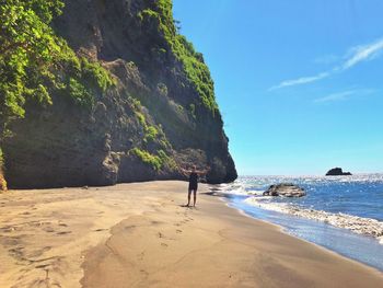 Man on rock at beach against sky