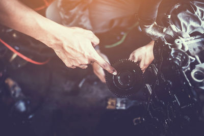 Cropped hands of mechanic repairing engine in workshop