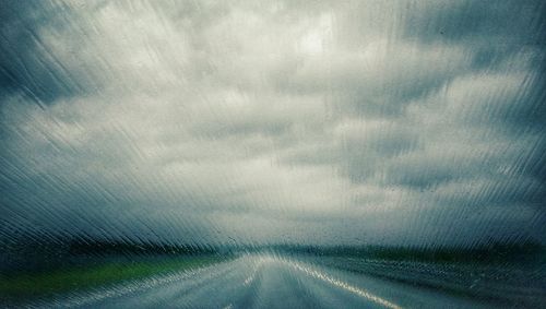 Road on landscape against storm clouds