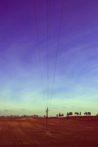 Electricity pylon on field against cloudy sky