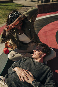 Woman protecting face of man from sunlight while lying in playground