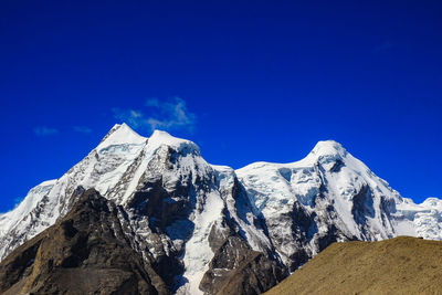 Scenic view of snowcapped mountains against blue sky