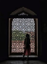 Rear view of woman standing against window in building