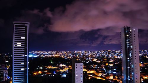 Illuminated towers in city against sky at night