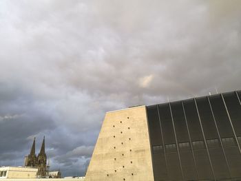 Low angle view of modern building against cloudy sky