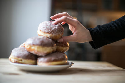 Cropped hand holding donut on table