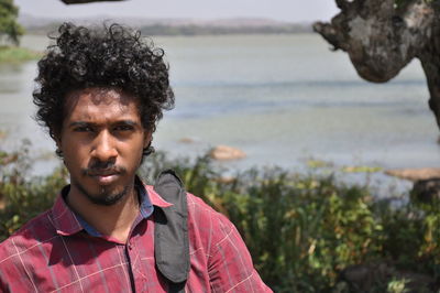 Portrait of man against lake during sunny day