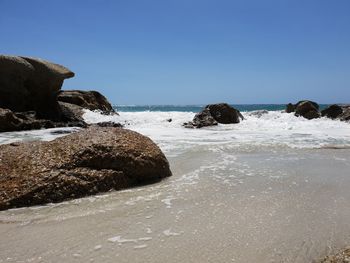 Rocks on beach against clear sky