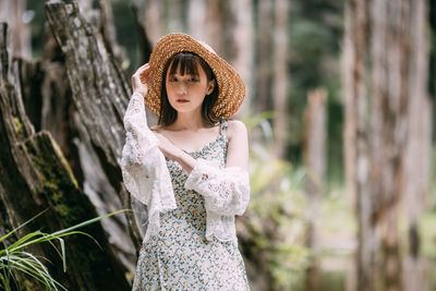 Young woman standing against trees