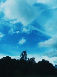 Low angle view of silhouette trees against blue sky