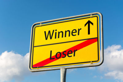 Low angle view of road sign against blue sky