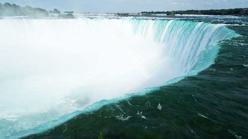 Scenic view of waterfall by sea