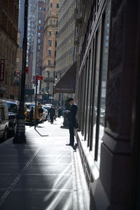 Rear view of people walking on street amidst buildings in city