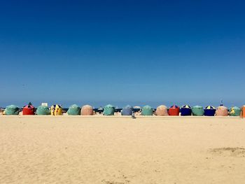 Scenic view of multi colored tents on beach against blue sky 