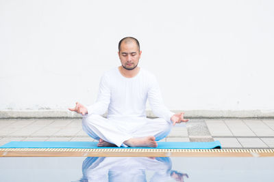 Full length of young man sitting on wall