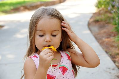 Cute girl with eyes closed smelling coneflower at park