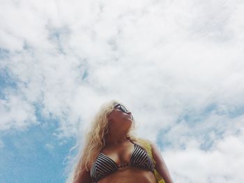 Low angle view of mid adult woman standing against cloudy sky